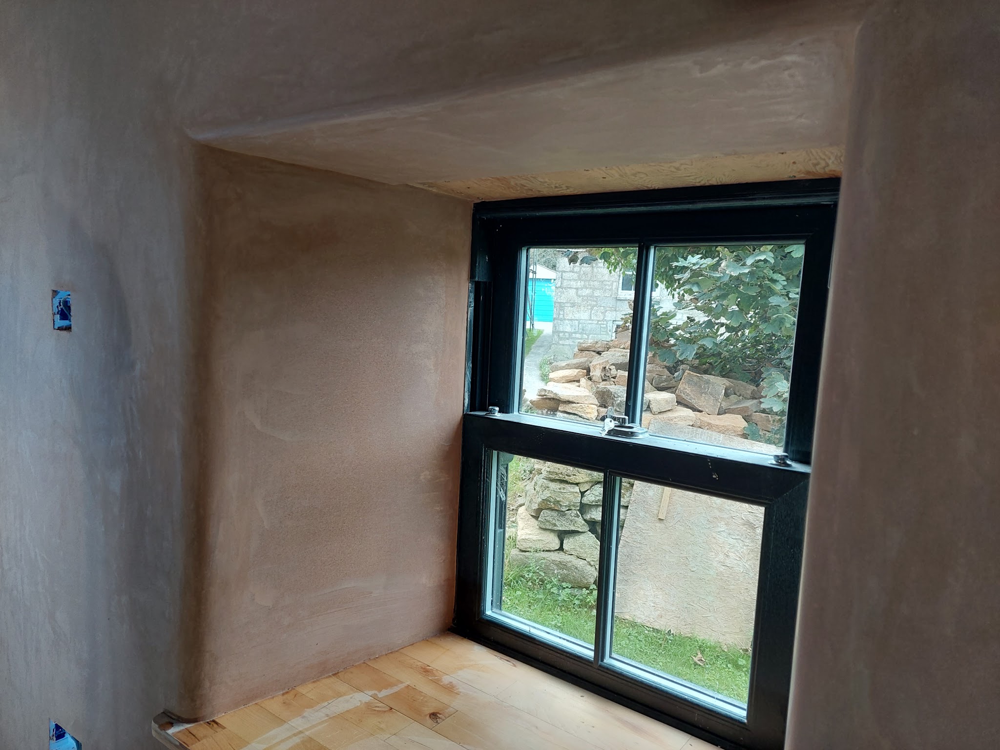 Deep window reveal freshly plastered around a dark-framed sash window