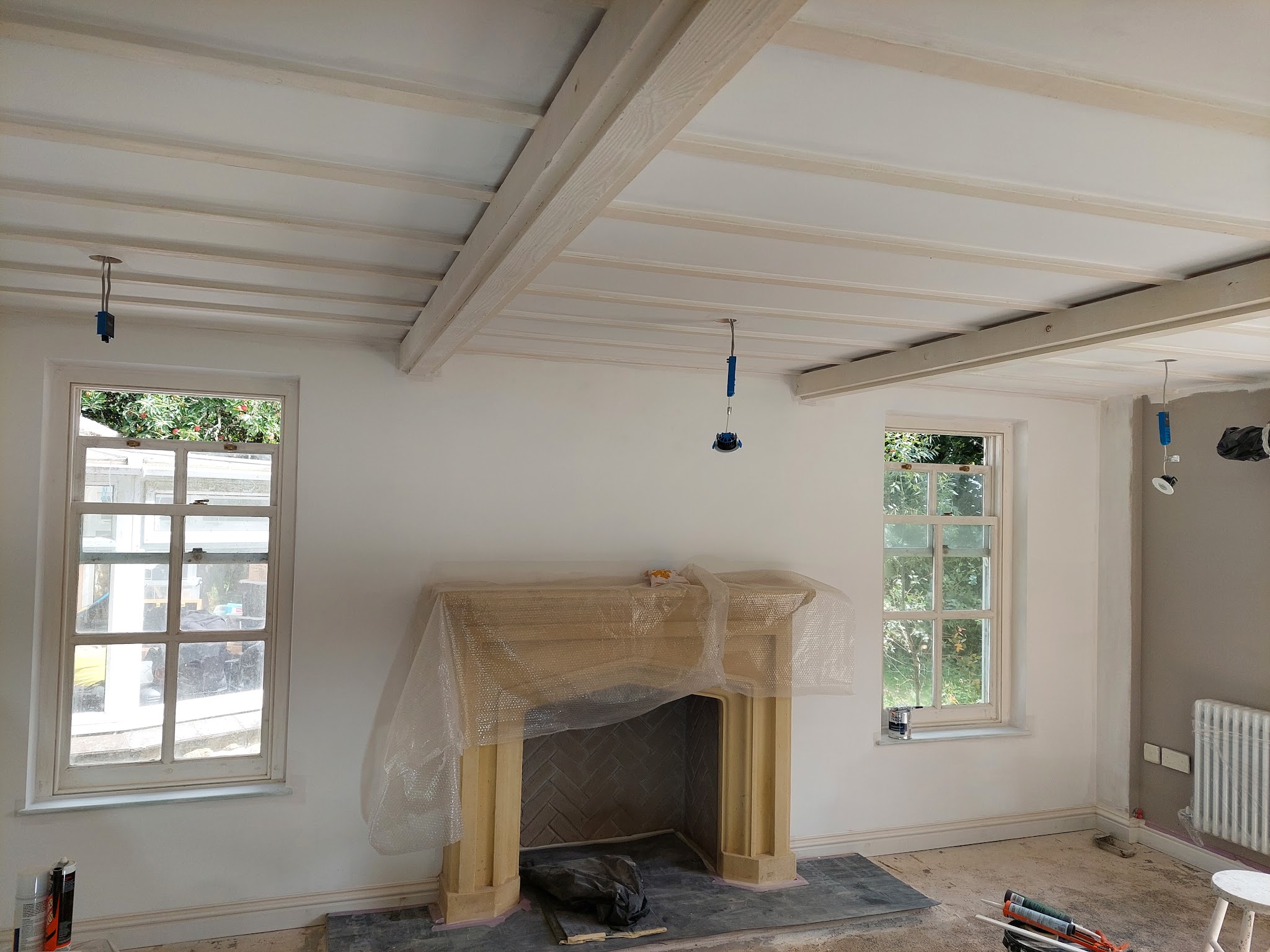 Living room with a beamed ceiling and smooth white walls around a stone fire surround